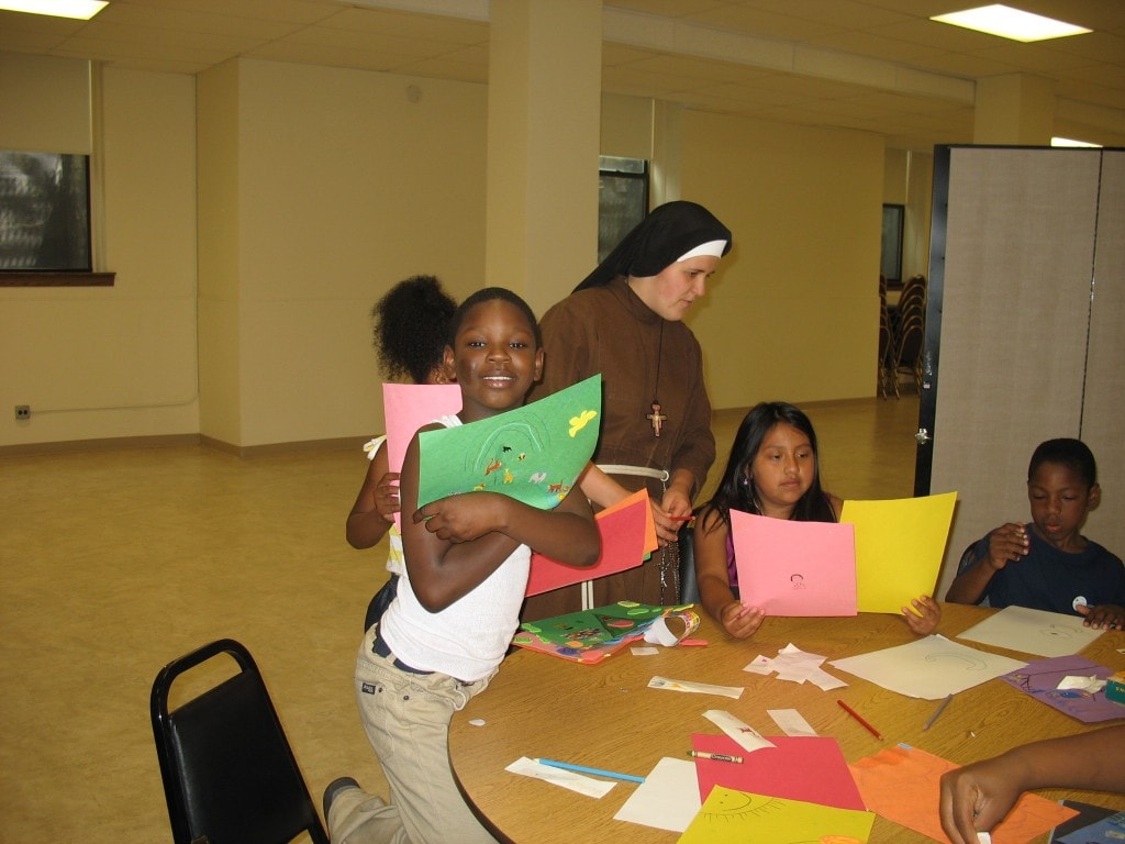 Sr. Kate helps kids as they draw pictures of God the Father and creation.