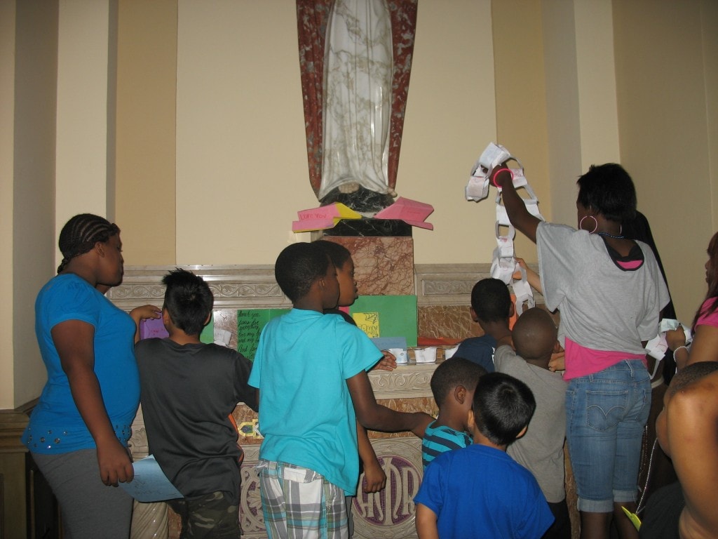 Kids lay the Gifts of the Holy Spirit by the Sacred Heart of Jesus Statue, where their Thank you letter to Jesus were also presented earlier that day.